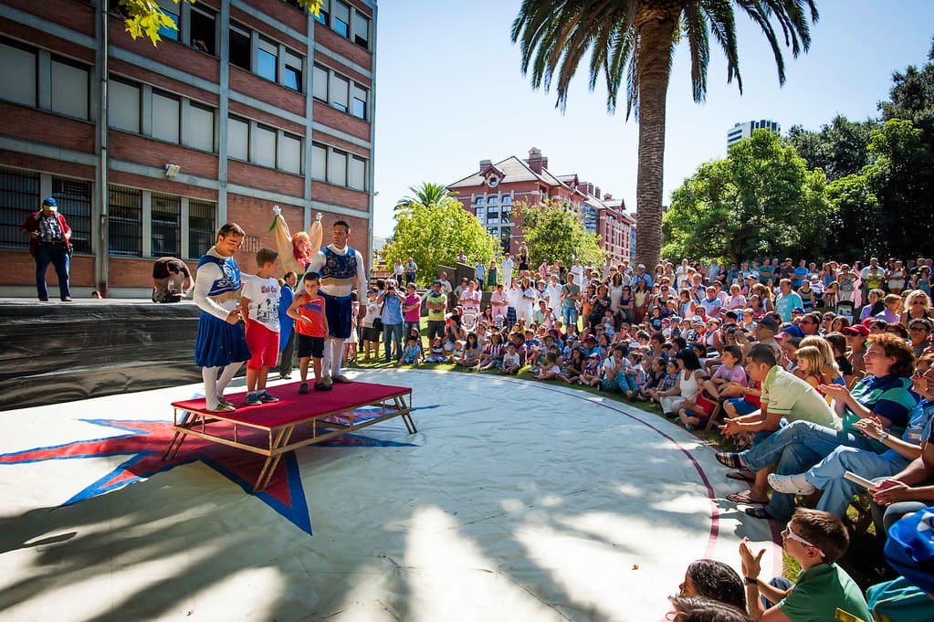 Crowds fill a tree-lined square in Bilbao around a performance stage during Aste Nagusia