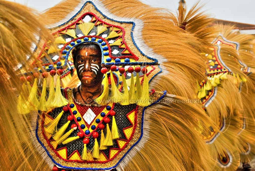 A dancer in an elaborate golden-feathered headdress and painted mask at Ati-Atihan