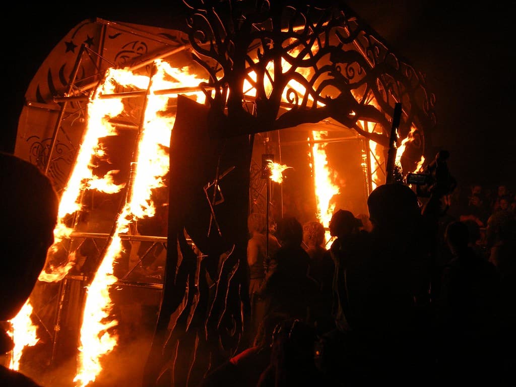 Flames run up a tall metal fire arch as crowds gather in the dark on Calton Hill during the Beltane Fire Festival