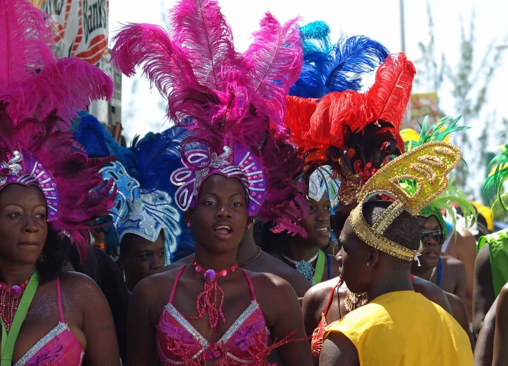 Masqueraders in pink and purple feathered headdresses dance in the Grand Kadooment parade in Barbados