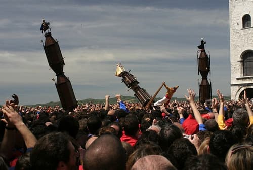 The three ceri of Gubbio tilt above a packed Piazza Grande as the crowd cheers during the Festa dei Ceri
