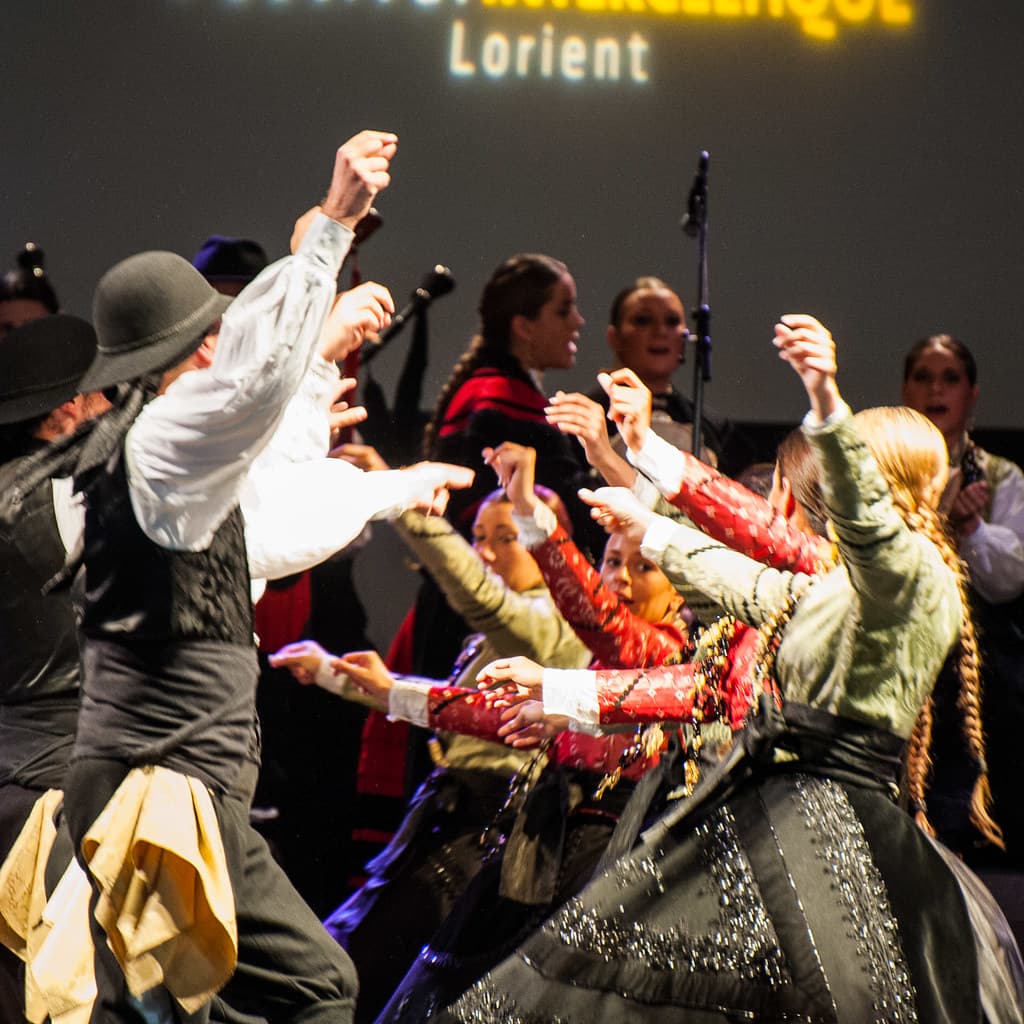Dancers in Breton costumes leap and swing on stage at the Festival Interceltique de Lorient