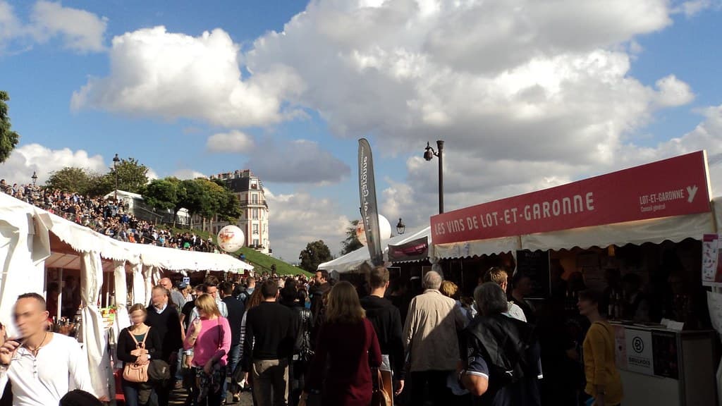 Crowds browse wine and regional food stalls under a wide sky at the Fête des Vendanges de Montmartre in Paris