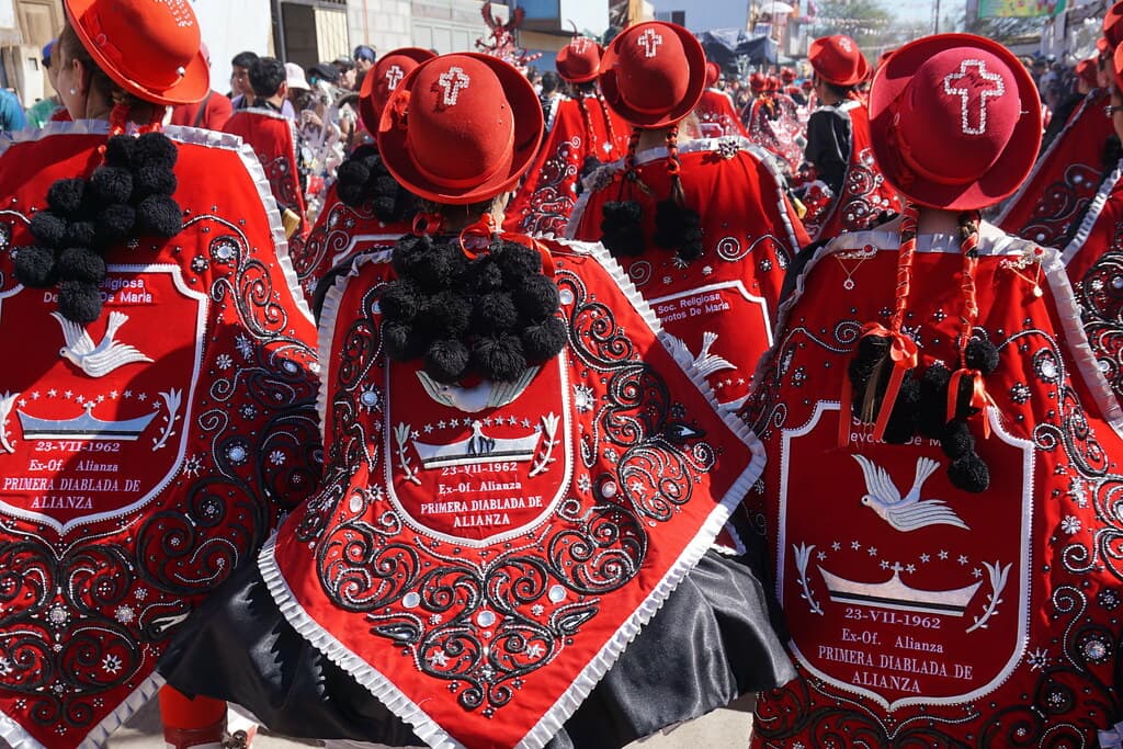 Dancers in red shawls embroidered with white doves and red hats parade in the streets of La Tirana
