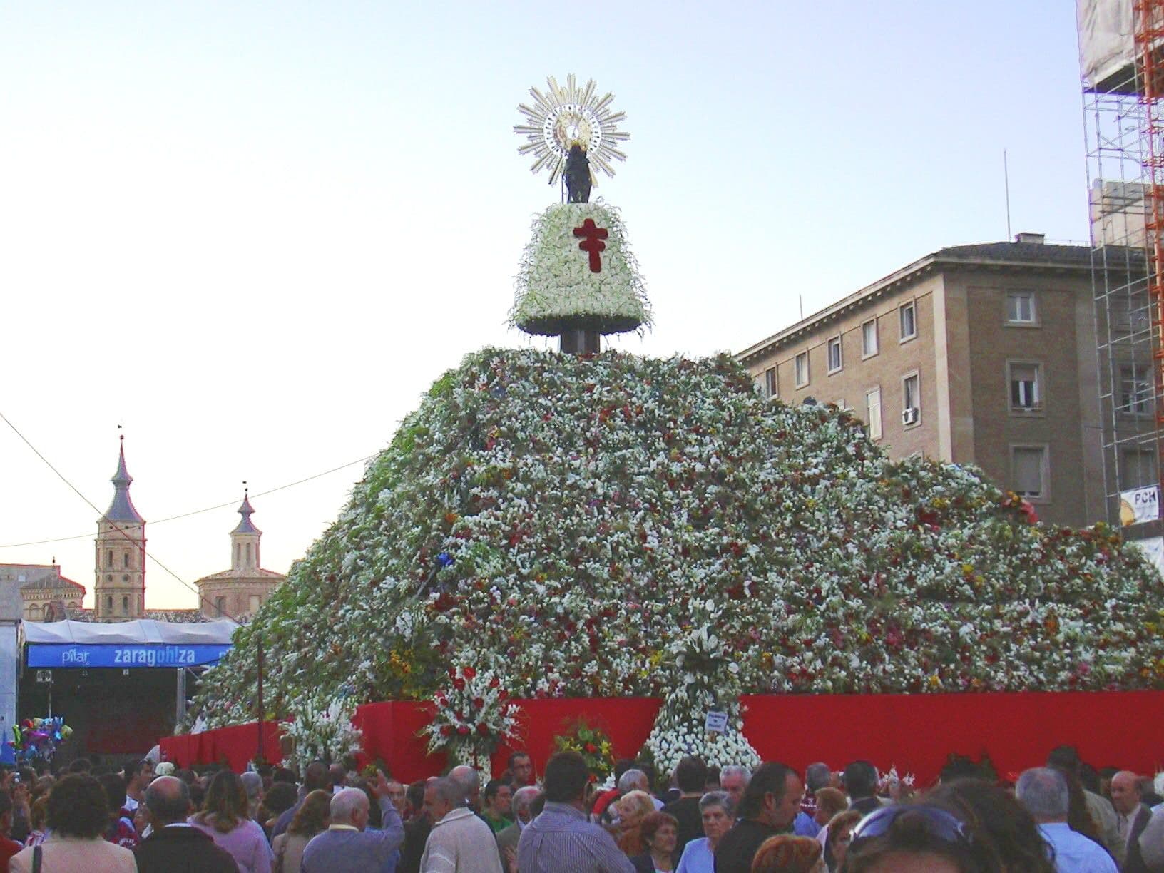 Crowds before the flower-covered image of the Virgin of the Pillar in Zaragoza's Plaza del Pilar during the Ofrenda de Flores