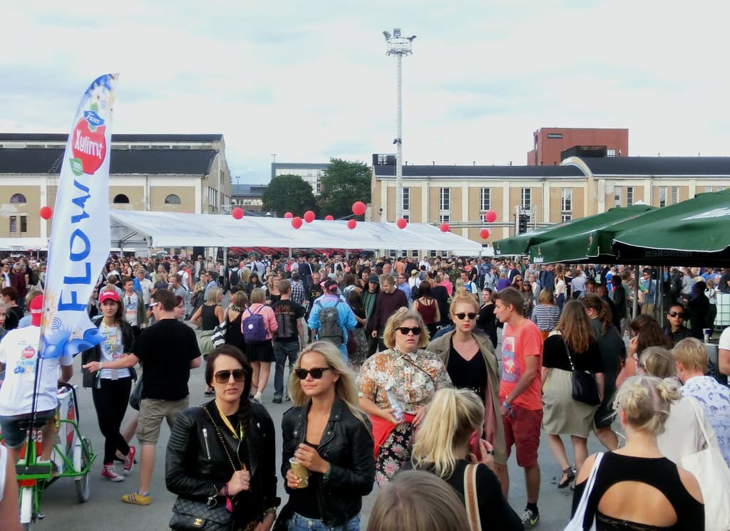 Festival-goers gather on the grass between the old brick buildings of Suvilahti at Flow Festival in Helsinki