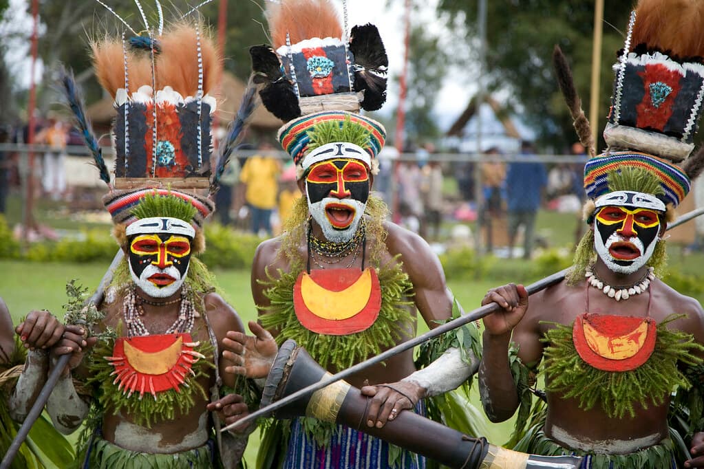 Highland performers with red, white and yellow painted faces, feather headdresses and shell necklaces at the Goroka Show