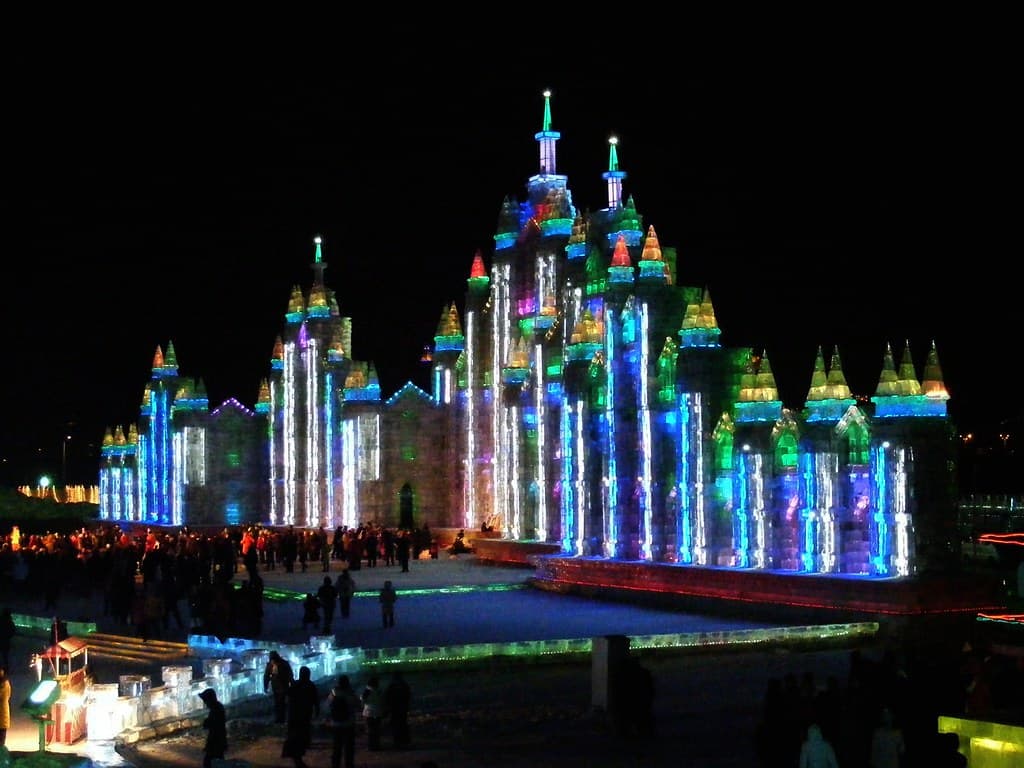 Illuminated ice castle towers glowing at night at the Harbin Ice and Snow Festival