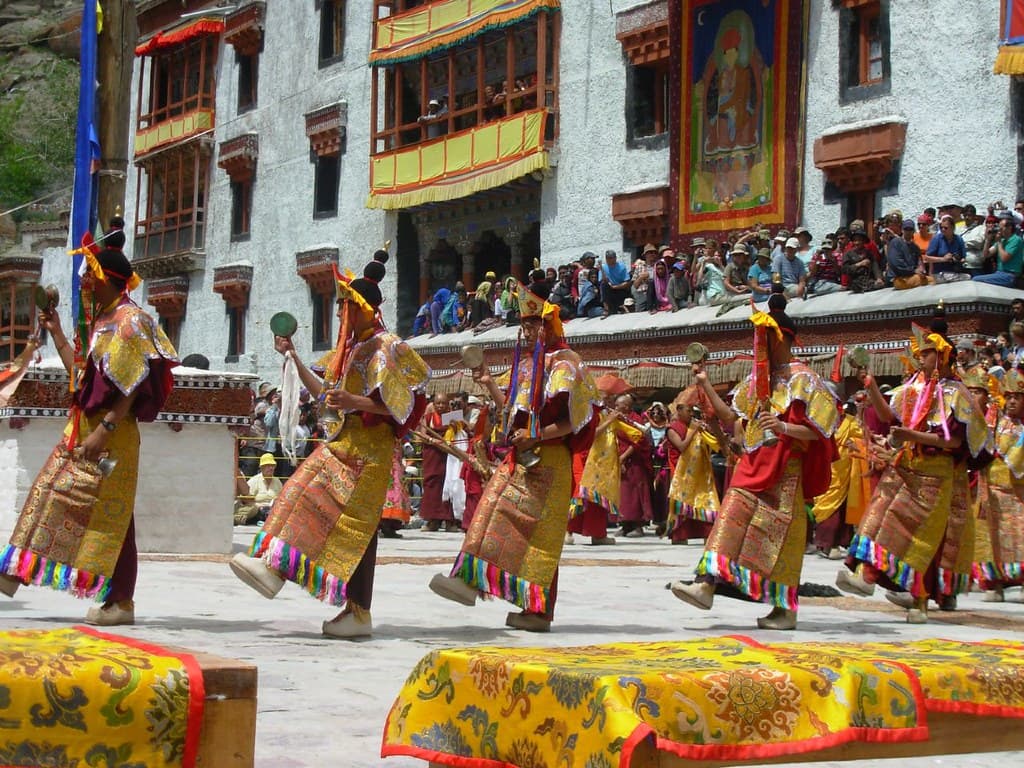 Masked monks in bright brocade robes perform a cham dance in the courtyard of Hemis Monastery, watched by crowds on the galleries