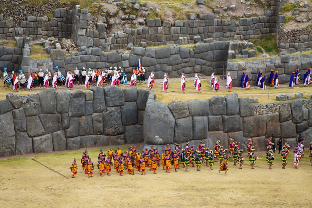 Hundreds of costumed performers in formation on the esplanade below the giant zigzag stone walls of Sacsayhuamán during Inti Raymi