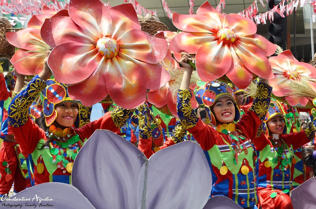Dancers in bright floral costumes on a parade float at the Kadayawan Festival in Davao