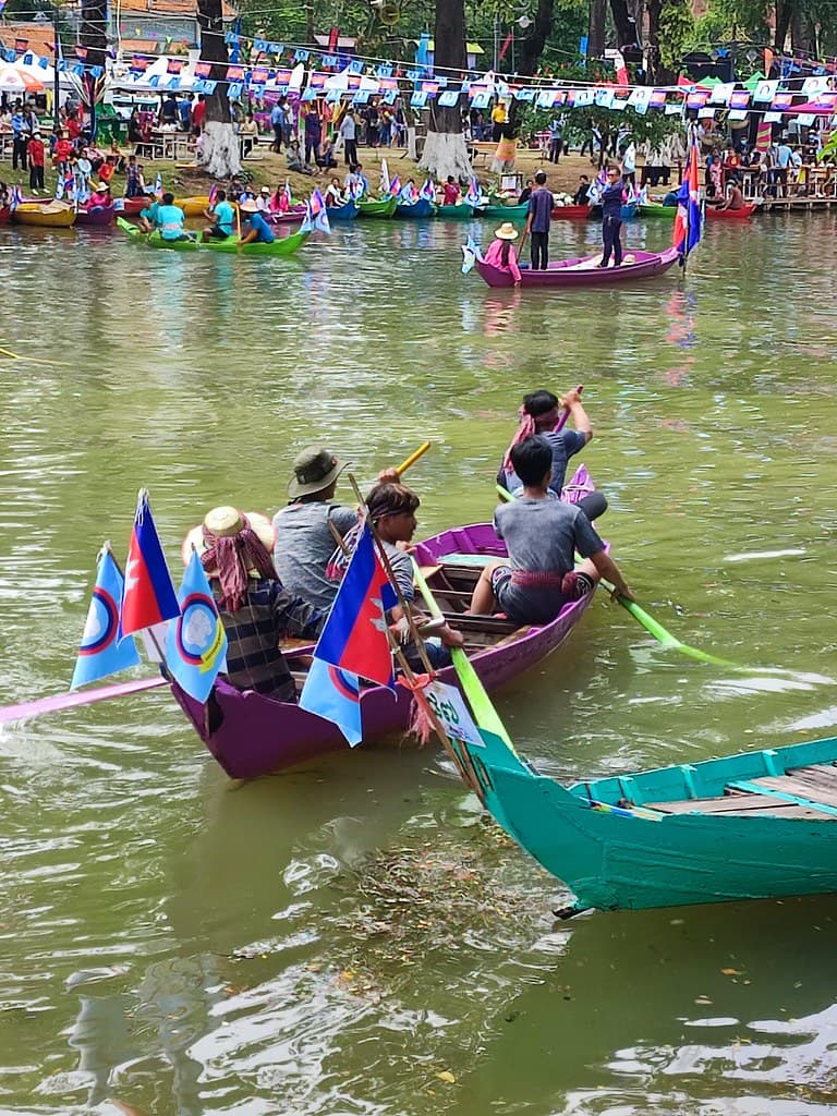Boats decorated with flags carry people along a canal lined with colourful bunting during Khmer New Year in Siem Reap