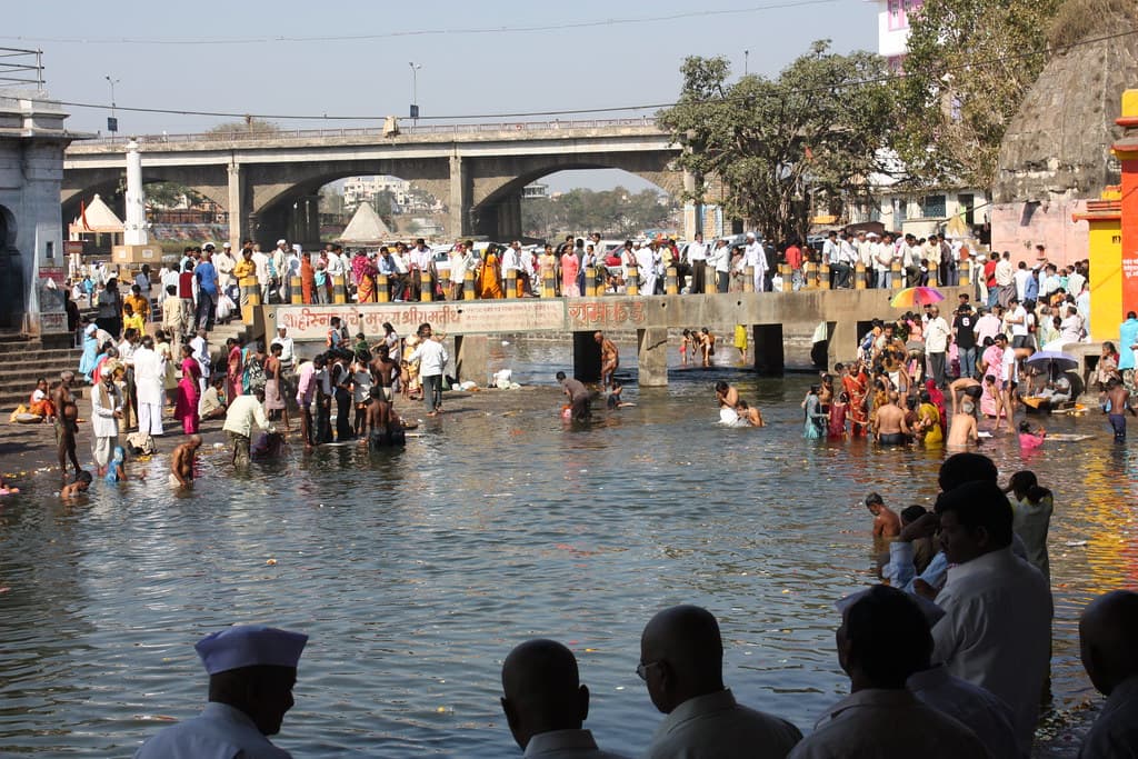 Crowds line the stepped banks and bridge of Ramkund on the Godavari river in Nashik as pilgrims bathe