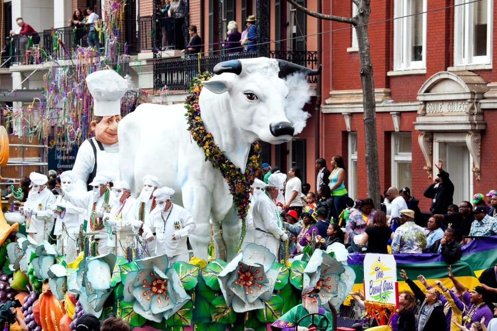A giant white bull float rolling through a New Orleans street during a Mardi Gras parade