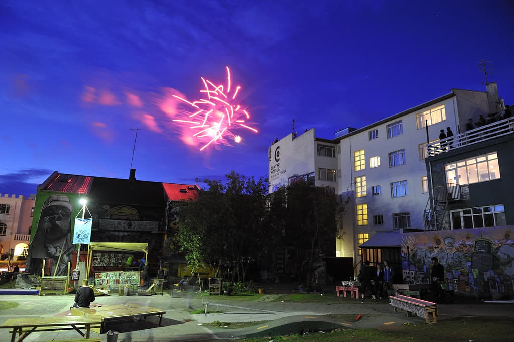 Fireworks burst in the blue night sky above buildings in Reykjavík on Culture Night
