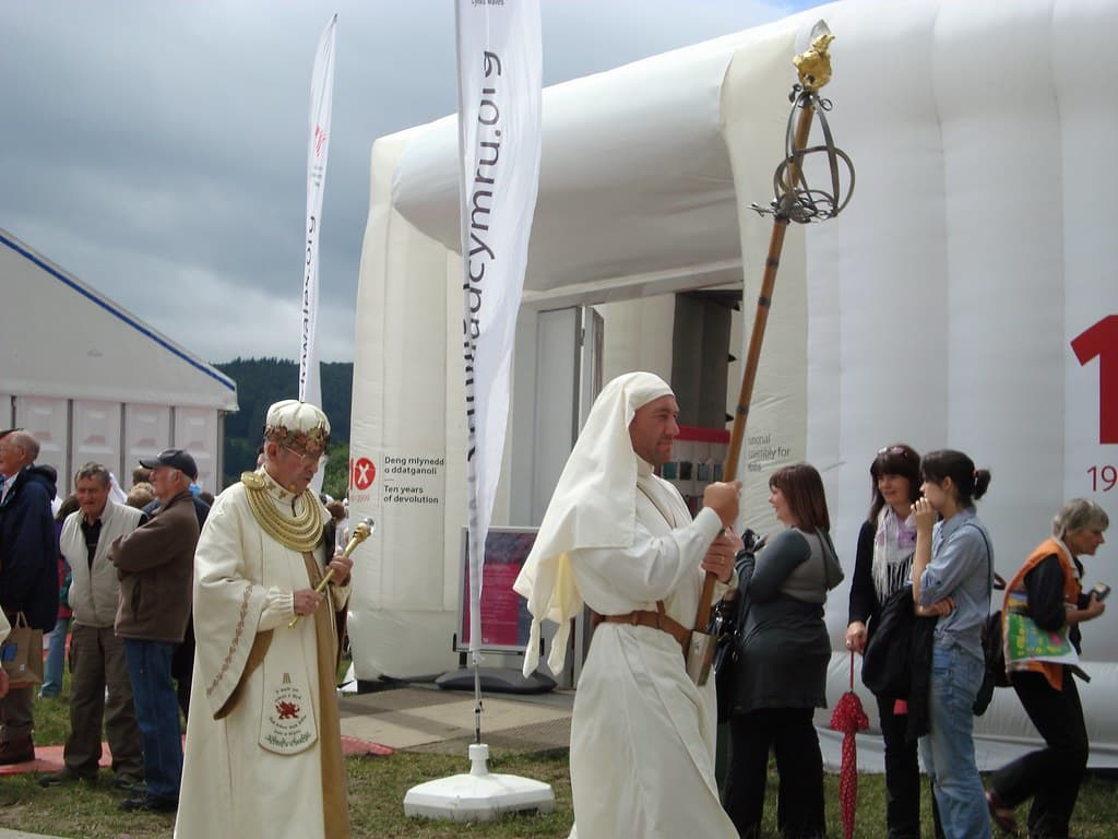 Robed members of the Gorsedd of Bards in white walk in procession on the Eisteddfod field in Wales