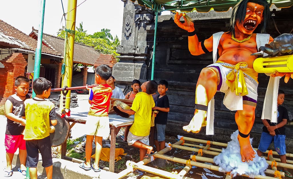 Children gathered around a colorful ogoh-ogoh figure in Bali ahead of Nyepi
