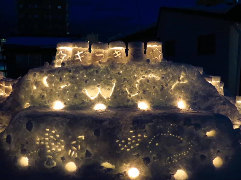 Rows of candles glow inside a large snow sculpture at night during the Otaru Snow Light Path