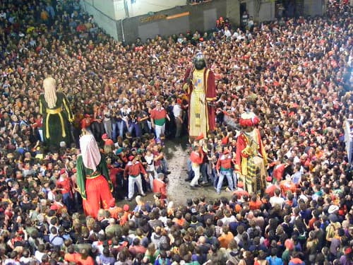 Giant figures dance in the middle of a dense crowd packed into Berga's main square during La Patum