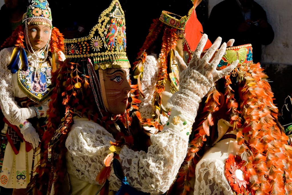 Masked dancers in elaborate embroidered costumes and crowns wave during the Virgen del Carmen fiesta in Paucartambo