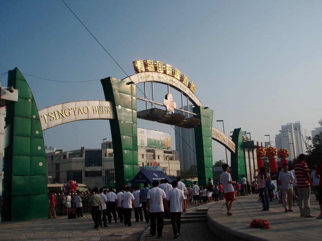Visitors walk under the green and gold entrance arch of the Qingdao International Beer Festival