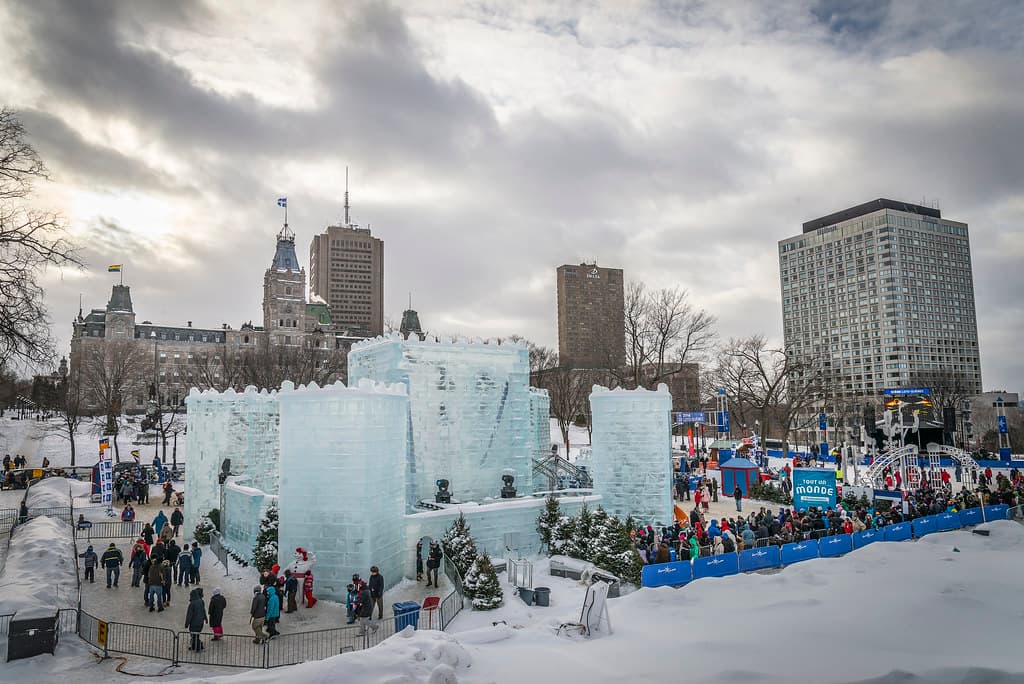 Ice sculptures and crowds in front of the Quebec City skyline at the Winter Carnival