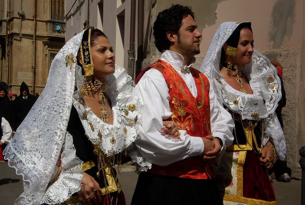 Young women and men in embroidered traditional Sardinian costumes walk in the Sant'Efisio procession in Cagliari
