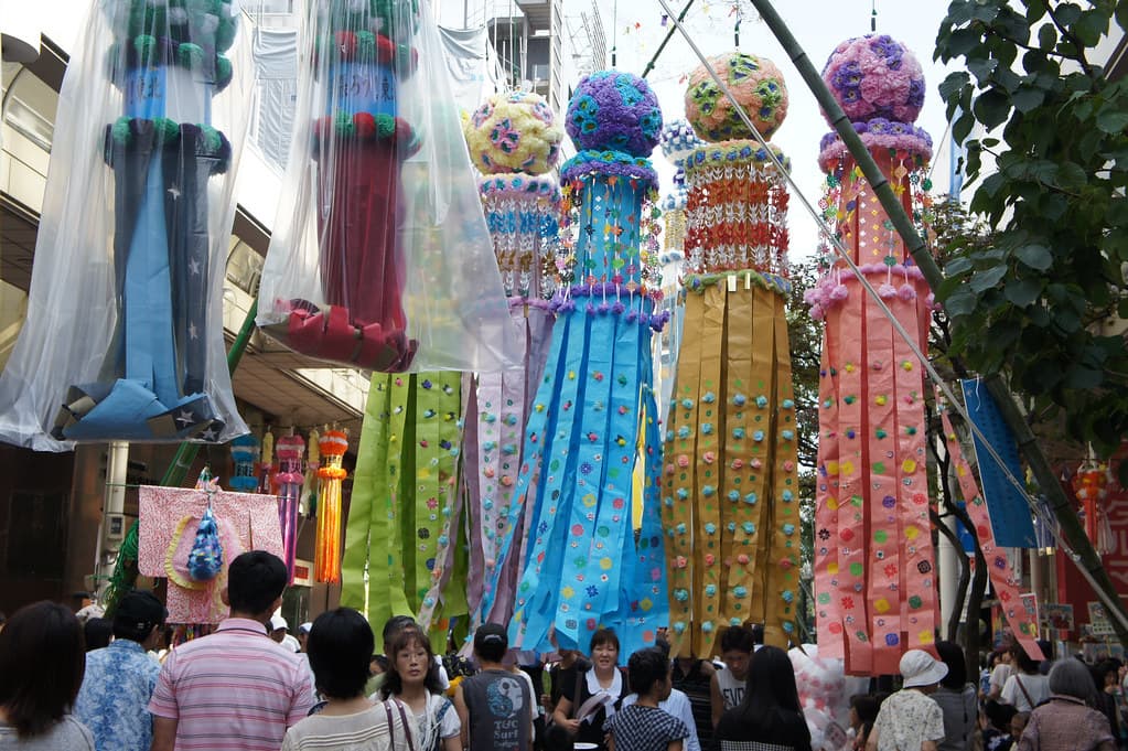 Giant Tanabata decorations with paper balls and long streamers hang over crowds in a Sendai shopping arcade