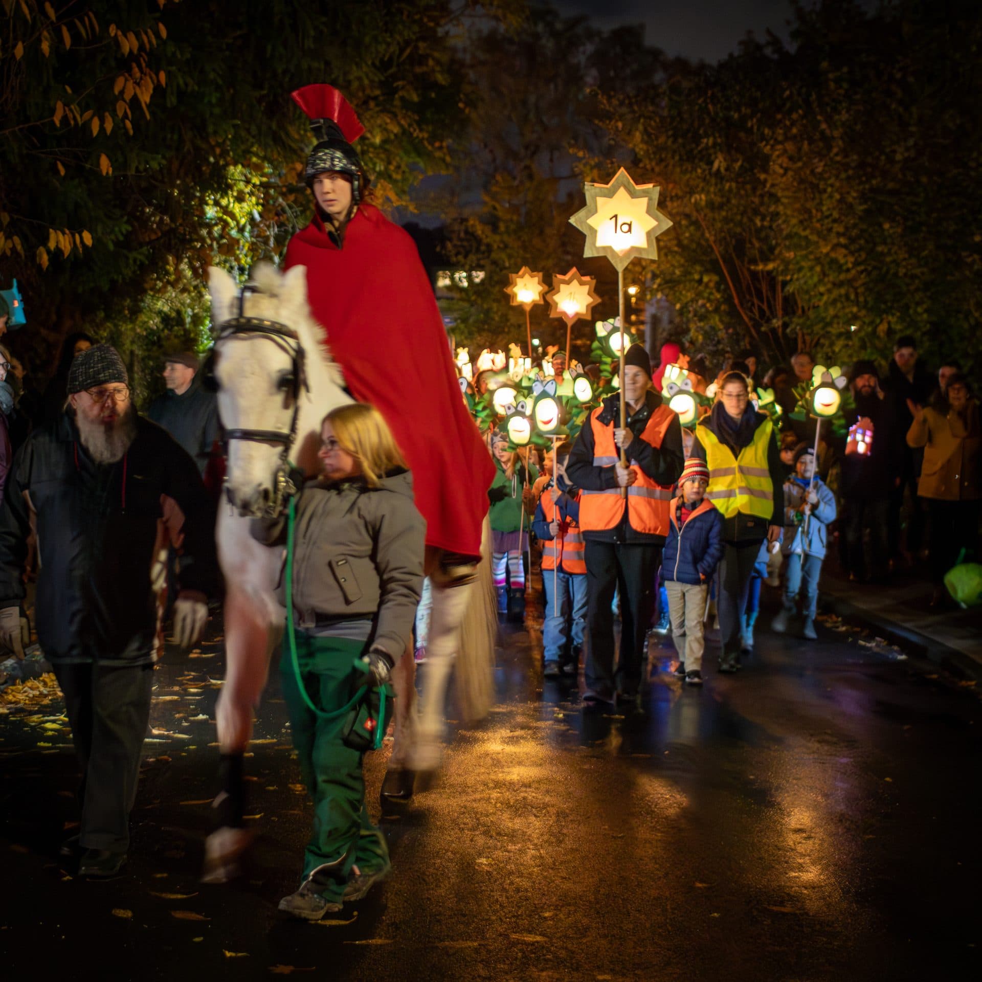 A rider dressed as St. Martin in a red cloak leads children carrying lanterns through Cologne at night