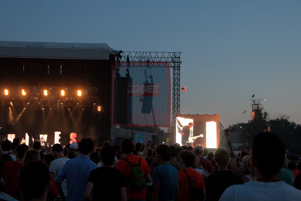 A crowd watches a big outdoor stage at dusk at the Sziget Festival in Budapest