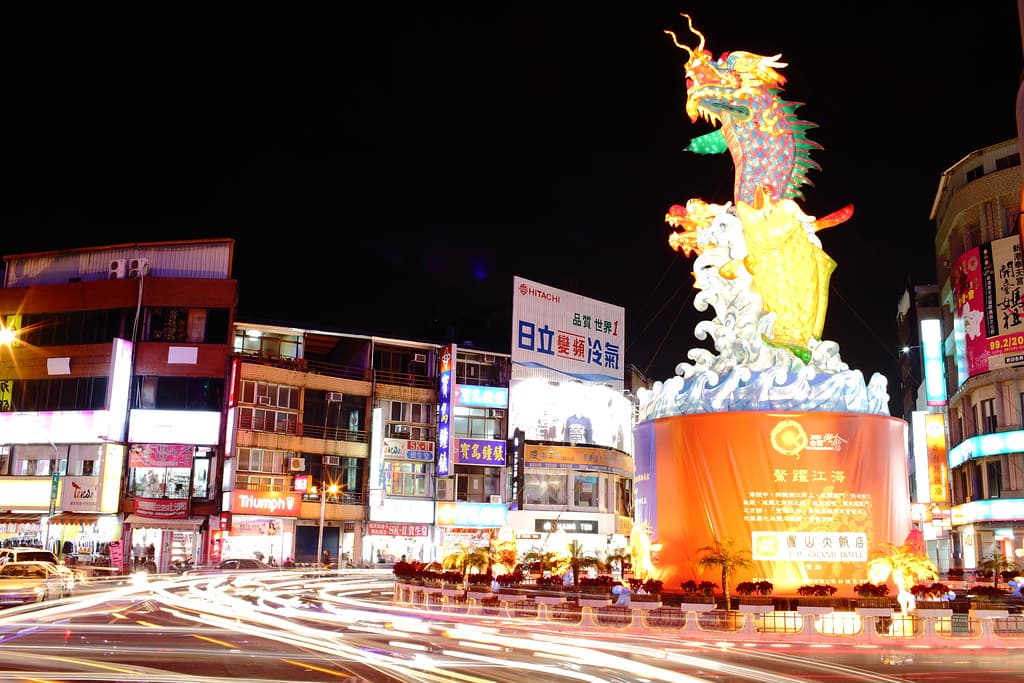 A giant lantern of a dragon fish rising from waves glows above a city square at night at the Taiwan Lantern Festival in Chiayi