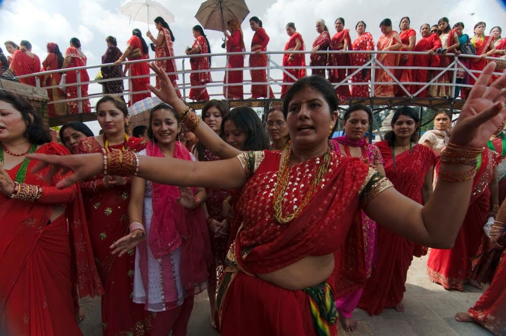 Women in red saris and bangles dance together in a crowd at the Pashupatinath temple in Kathmandu during Teej