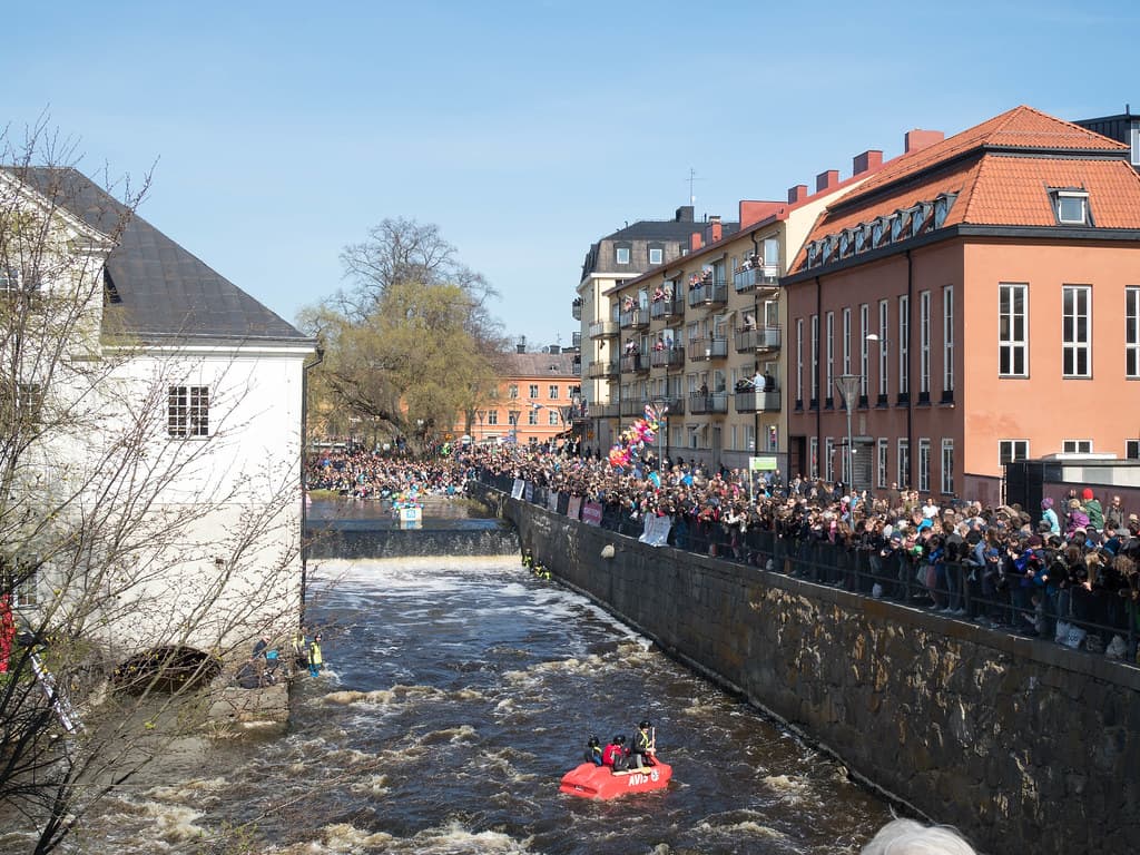 Crowds line the riverbanks and bridges in Uppsala as rafts head down the rapids of the Fyris River on Valborg