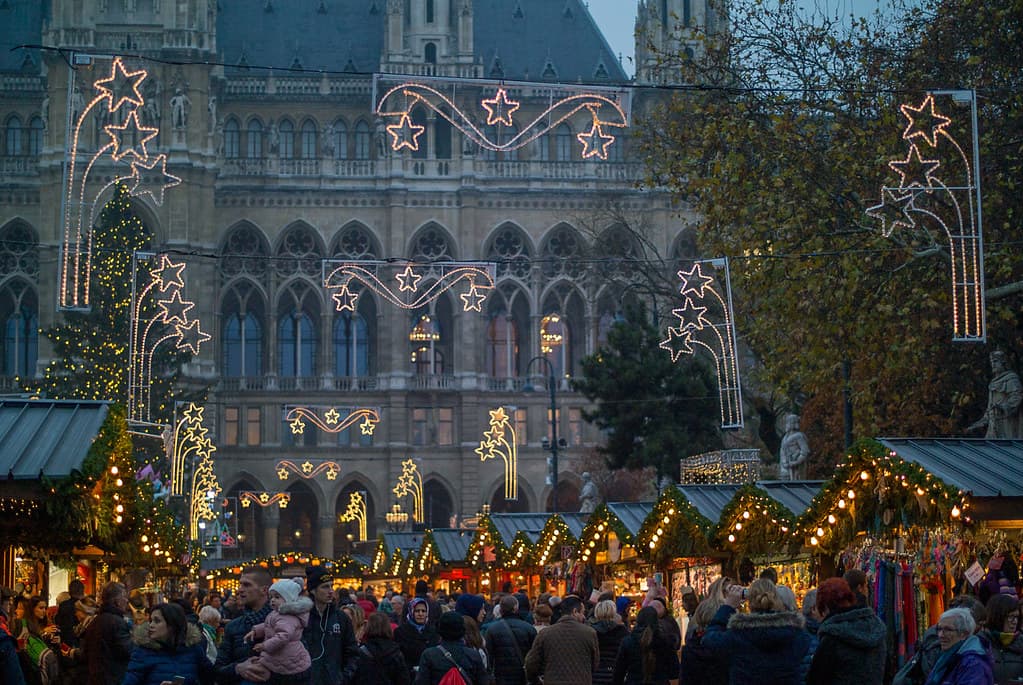 Christmas market stalls and lights in front of Vienna's City Hall at dusk
