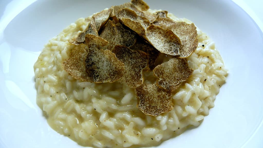 A plate of risotto topped with thin shavings of white truffle