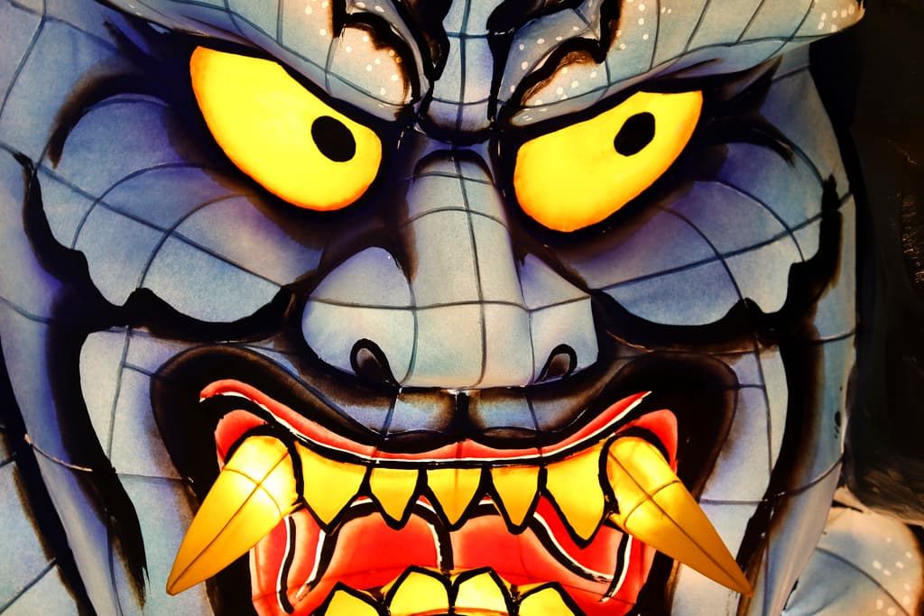 A fierce, glowing Nebuta warrior face with yellow eyes
