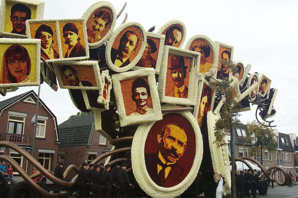 A dahlia-covered float decorated with framed portraits in the shape of a family tree passes houses in Zundert