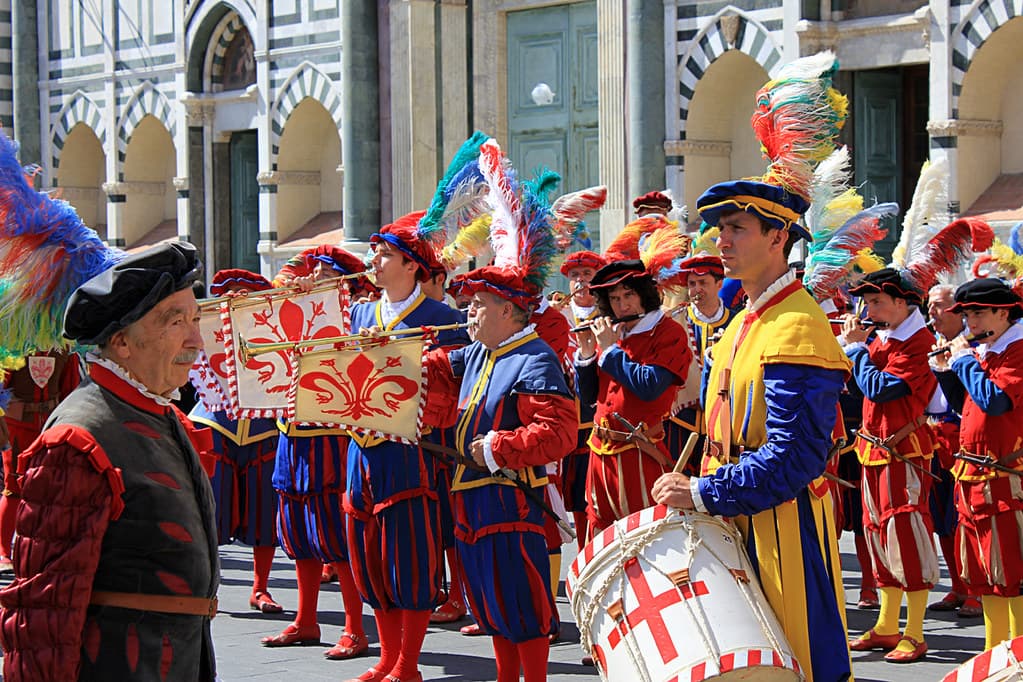 Drummers and standard-bearers in bright Renaissance costume and feathered hats parade before a calcio storico final in Florence