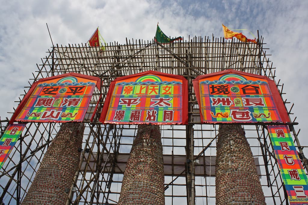 Towers of buns stacked on bamboo scaffolding, with colourful paper banners covered in Chinese characters