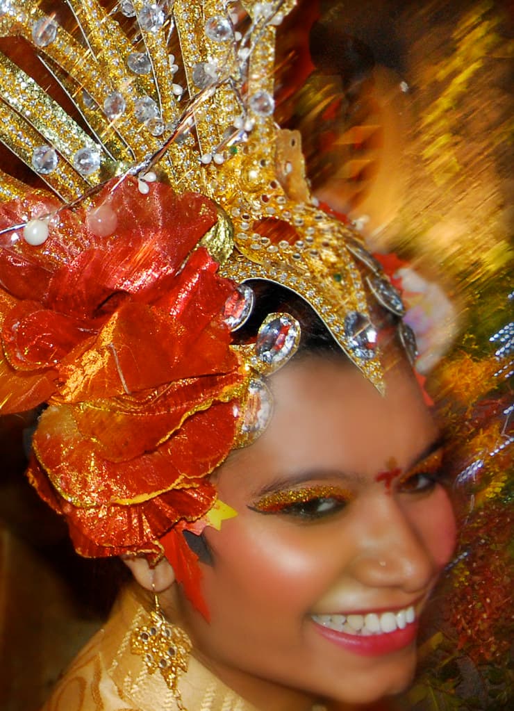 A smiling Chingay performer in a huge orange and gold feathered headdress