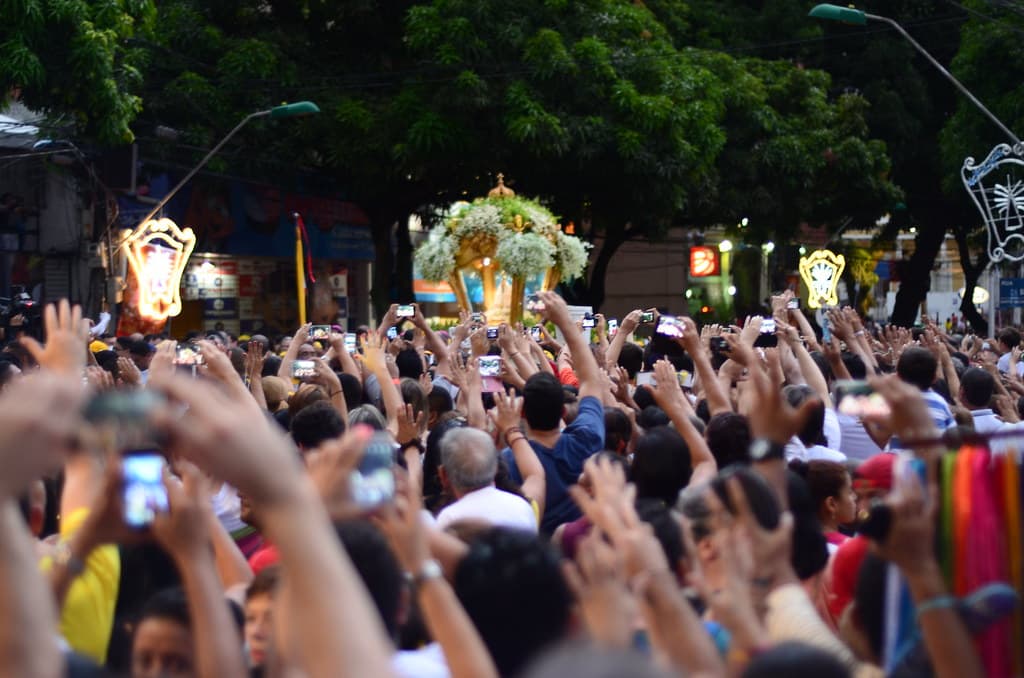 Crowds raise their hands as the flower-covered carriage of Our Lady of Nazareth passes through Belém during the Círio