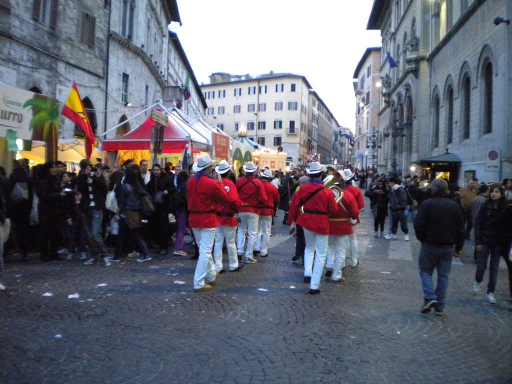 A marching band in red jackets parades along Perugia's Corso Vannucci during Eurochocolate