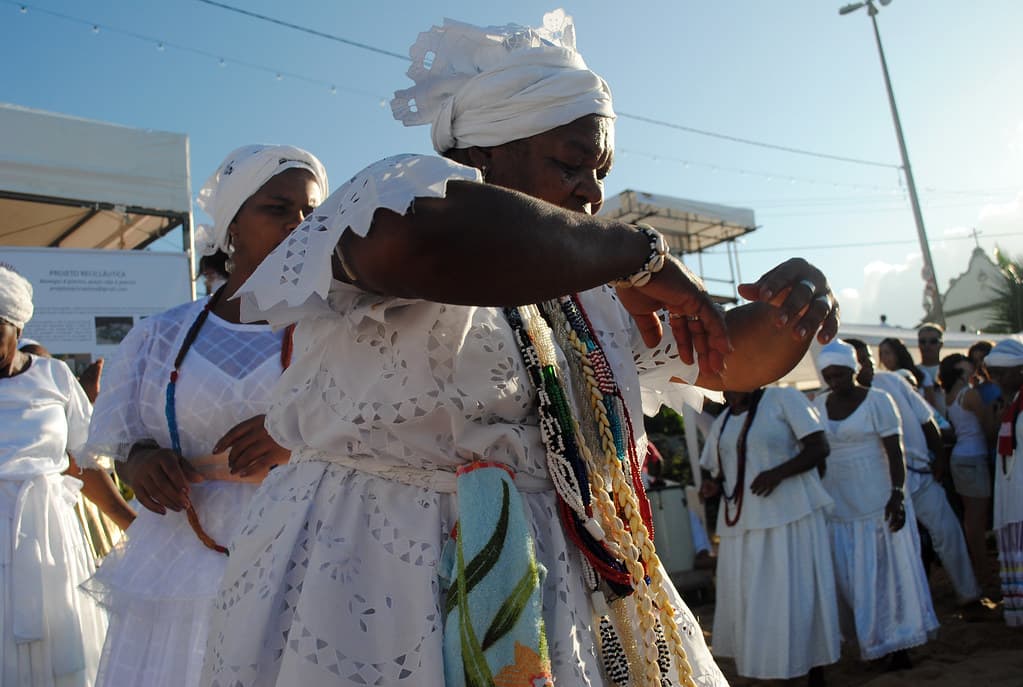 Women in white dresses and head wraps take part in a Candomblé ritual on the beach at Rio Vermelho