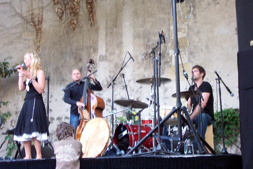 A singer and band with double bass and drums perform outdoors against an old stone wall in Paris on the Fête de la Musique