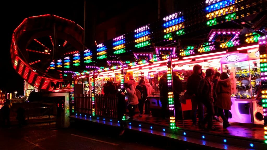 Fairground rides and food stalls lit up in neon colours at night during Edinburgh's Hogmanay