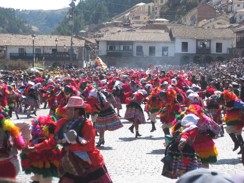 Dancers in red, pink and multicoloured Andean costumes fill a Cusco street in a procession during Inti Raymi