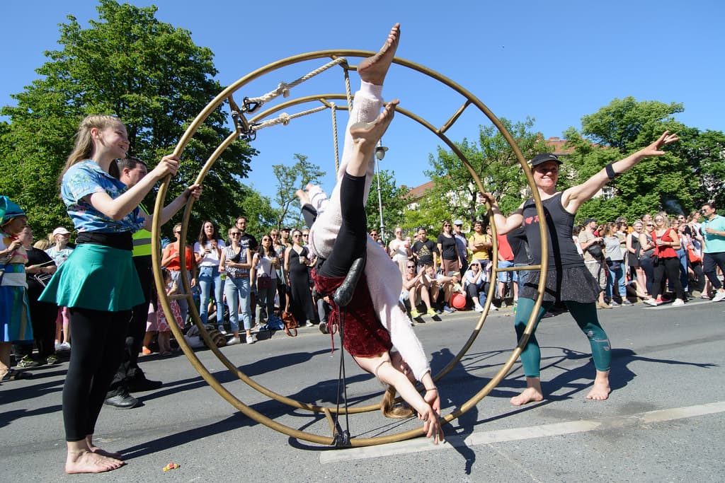 A performer spins inside a large metal wheel in the street as crowds watch at the Karneval der Kulturen in Berlin