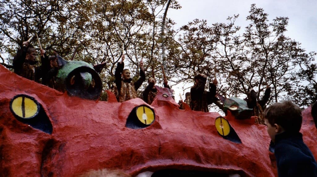 A giant red cat float with yellow eyes carries performers through the Kattenstoet parade in Ypres