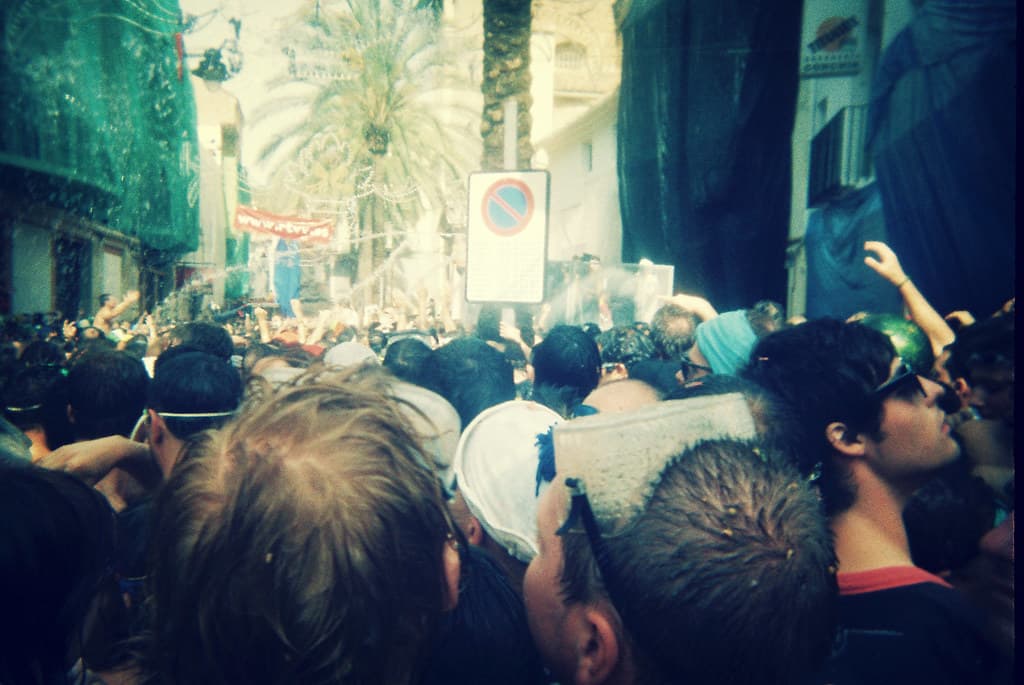 A tightly packed crowd in a Buñol street waits for the tomatoes to arrive, seen from inside the crowd