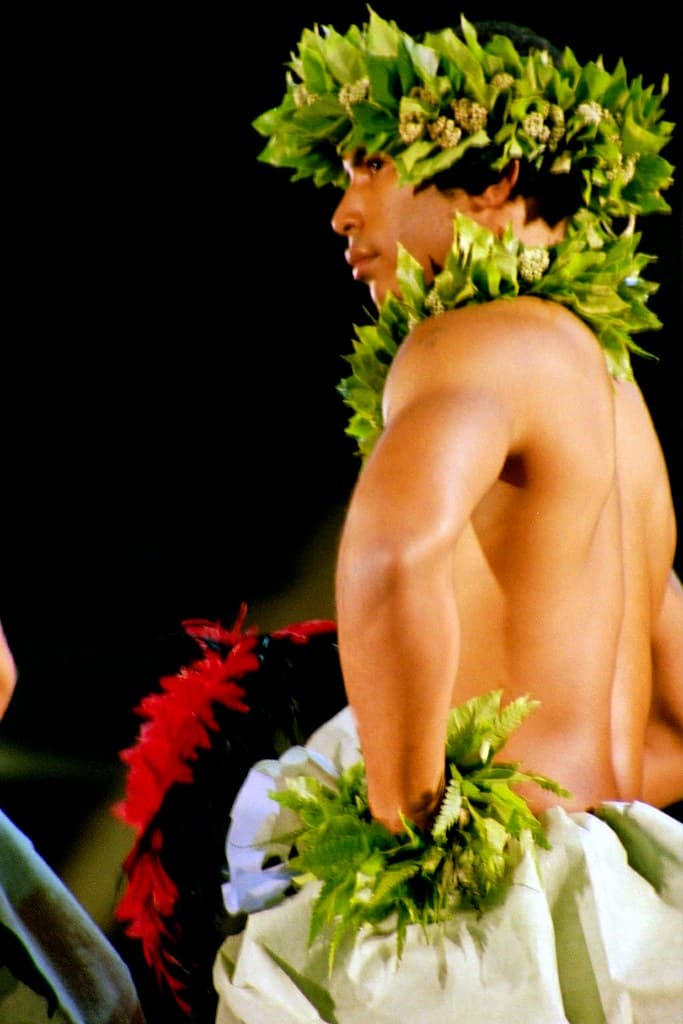 A male hula dancer with a leaf lei and green crown performs at the Merrie Monarch Festival